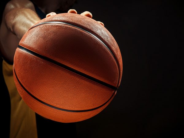 Jogador segurando bola de basquete em fundo preto